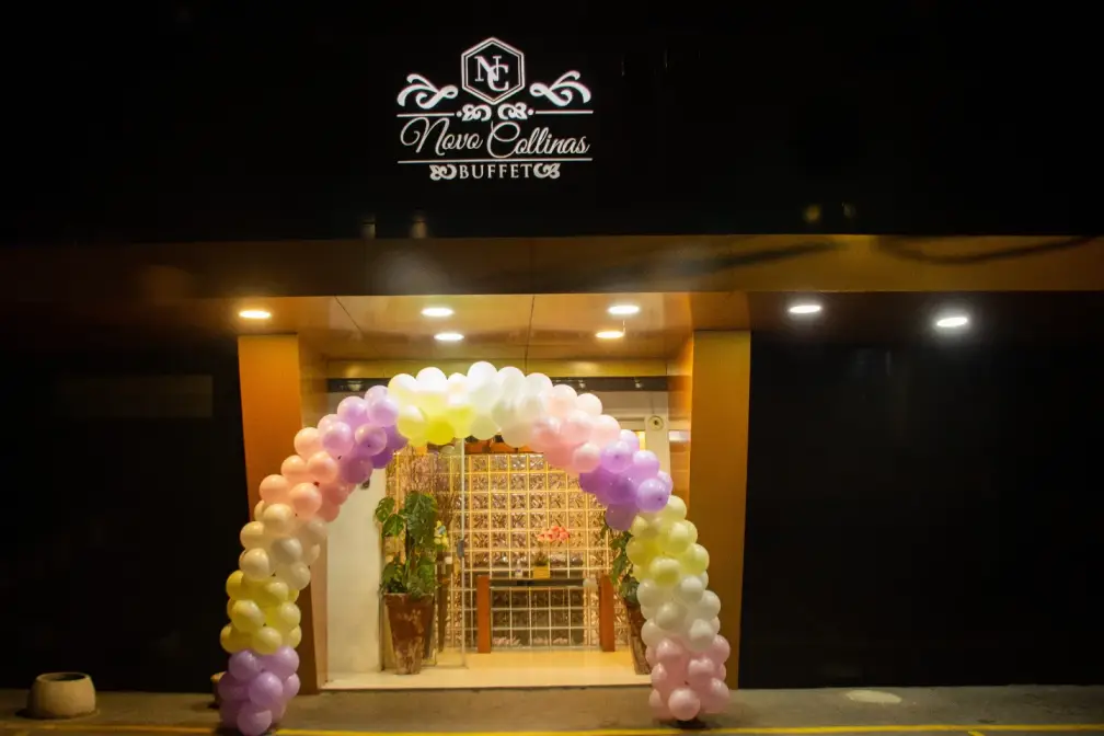 Fachada iluminada do Novo Collinas Buffet com arco de balões