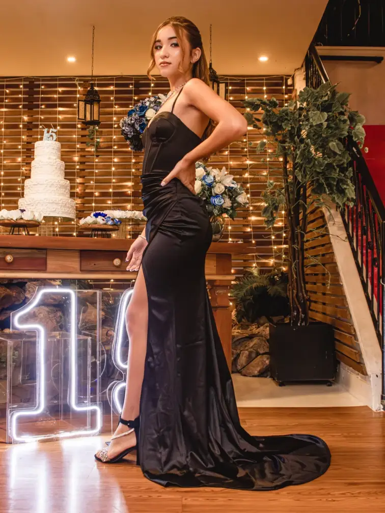 Debutante de vestido longo ao lado do neon 15 e da mesa do bolo