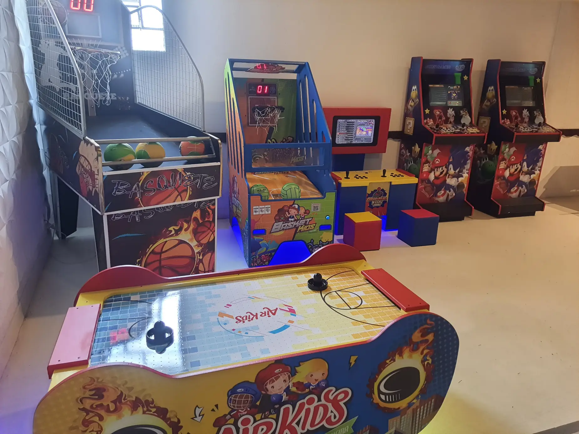 Área de games com basquete, air hockey e fliperamas